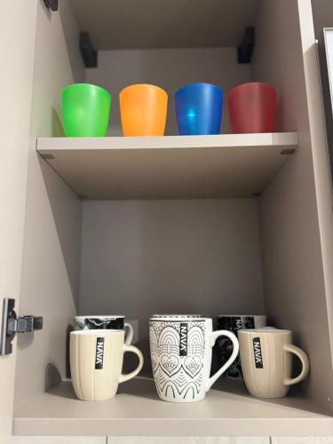 four colorful cups sitting on shelves in a cupboard at Anna's House in Kos Town
