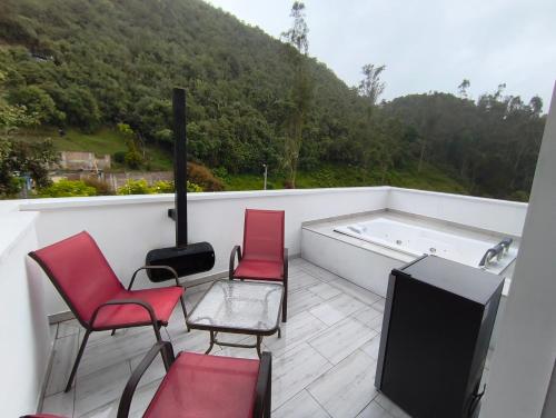 a balcony with chairs and a tv and a tub at Mirador samsara Penthouse !Jacuzzi al aire libre! in La Calera