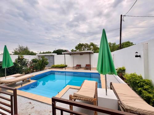 a swimming pool with chairs and umbrellas on a patio at Karibu in Gulioni