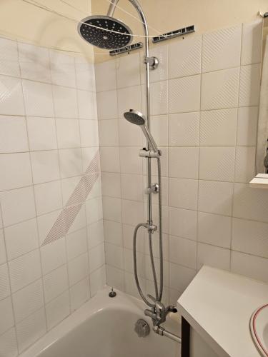 a shower in a white tiled bathroom with a tub at Le balcon du Jura in Lélex
