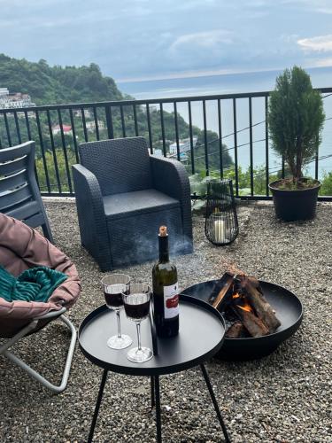 a bottle of wine and two glasses on a table at Villa Deluxe Kvariati in Kvariati