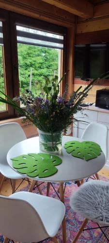 a white table with a vase of flowers on it at Chutor Grzegorza in Wysowa-Zdrój
