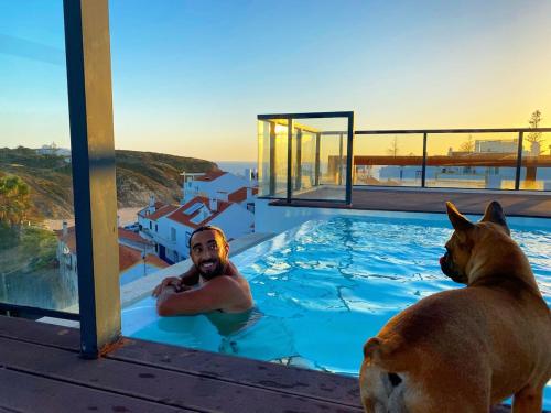 a man and a dog in a swimming pool at Apartment T3, sea view, swimming pool- Casa do Mar in Zambujeira do Mar