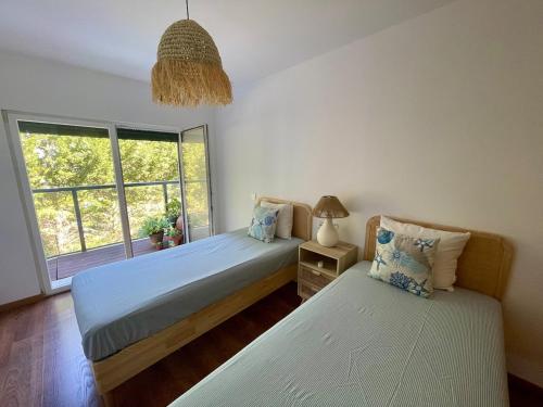a bedroom with two beds and a window at Apartment T3, sea view, swimming pool- Casa do Mar in Zambujeira do Mar