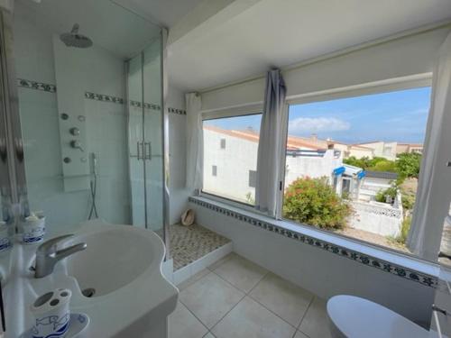 une salle de bain avec une baignoire, un lavabo et une fenêtre dans l'établissement Maison familiale à 100m de la Plage 8ARGO83, à Saint Pierre La Mer