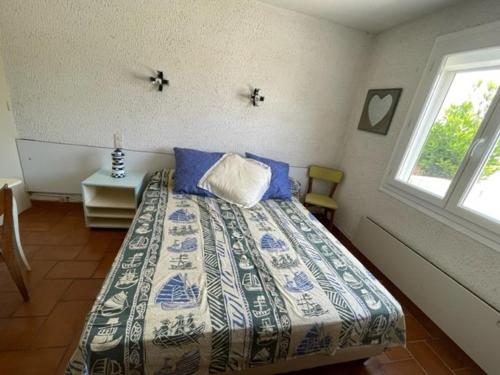 une chambre avec un lit avec des oreillers bleus et une fenêtre dans l'établissement Maison familiale à 100m de la Plage 8ARGO83, à Saint Pierre La Mer