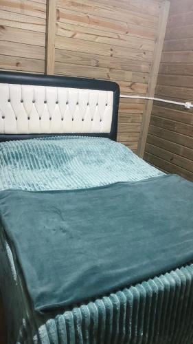 a bed with a green blanket on top of it at Cabana Vale das Pedras in Pedras Grandes