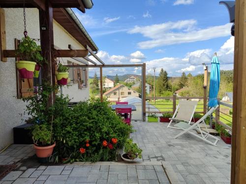 a patio with a chair and a umbrella and some plants at Appartement du Pré Nouveau in Prénovel