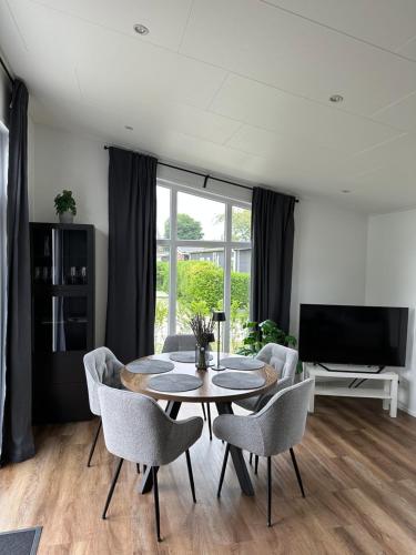 a living room with a table and chairs and a television at In Seenähe - Modernes Chalet im Ferienpark De Veerstal - familienfreundlich! in Lathum