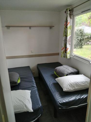 deux lits dans une petite pièce avec une fenêtre dans l'établissement Camping rivages des Landes, à Aureilhan