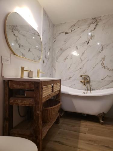 une salle de bain avec une baignoire, un lavabo et un miroir dans l'établissement Le clocher de Castries, à Castries