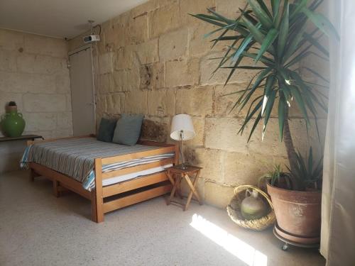 une chambre avec un lit et une plante contre un mur de briques dans l'établissement Le clocher de Castries, à Castries