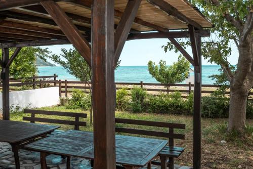 a picnic table under a pergola overlooking the ocean at Duchess Eva's Seafront Guesthouse in Chorefto
