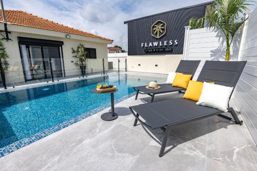 a patio with a chair and a table next to a pool at וילה פלואלס בוטיק in Shahar