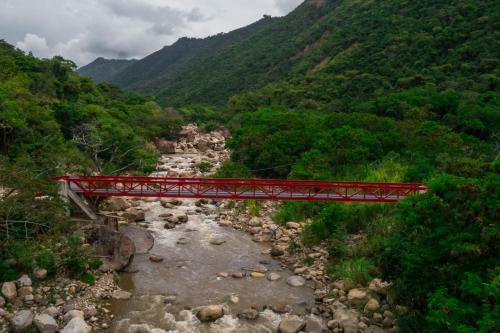 a red bridge over a river in a valley at HCR Hotel y Centro de Convenciones Chinauta Real in Fusagasuga