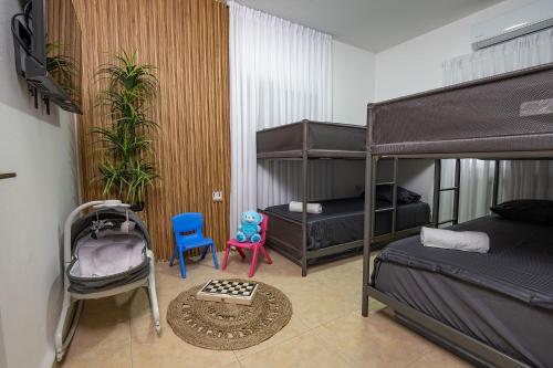 a bedroom with two bunk beds and a table and chairs at וילה פלואלס בוטיק in Shahar