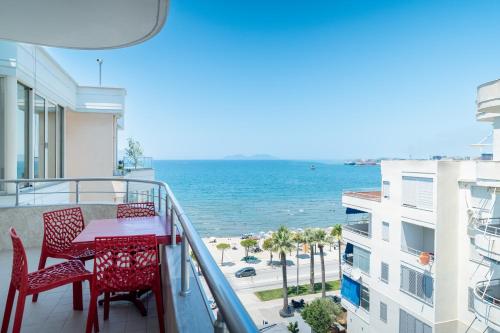 a balcony with a red table and chairs and the ocean at Apartments Vlora Holidays in Vlorë
