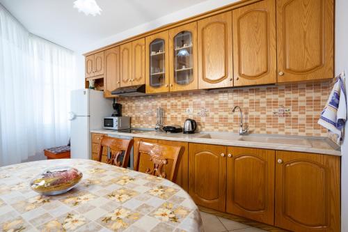 a kitchen with wooden cabinets and a table and a refrigerator at Apartments Vlora Holidays in Vlorë