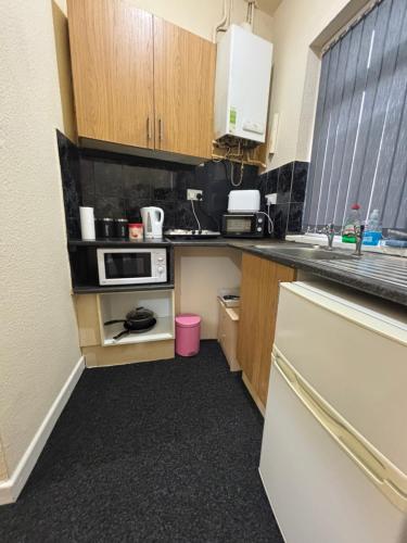 a small kitchen with wooden cabinets and a pink trash can at Simple Lodge in Wakefield