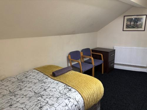 a bedroom with a bed and two chairs and a desk at Simple Lodge in Wakefield