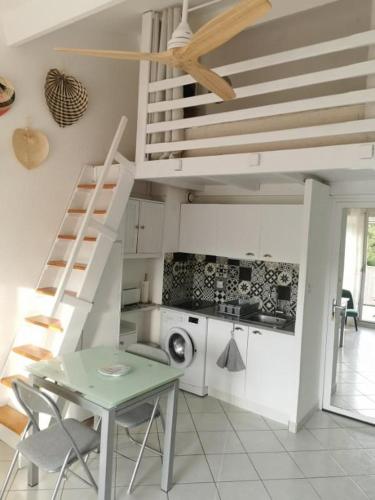 une cuisine blanche avec une table et un escalier dans l'établissement Appartement T2 Cabine, mezzanine Saint Pierre la mer 4oliv41, à Saint Pierre La Mer