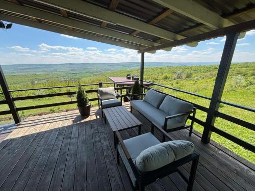 a porch with a couch and chairs on a deck at Căsuța din Deal 
