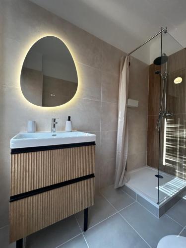 une salle de bain avec un lavabo, une douche et un miroir dans l'établissement Le nid marin, à Saint-Nazaire