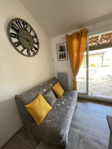 un salon avec un canapé et une horloge au mur dans l'établissement Pavillon idéal famille avec piscine 800m des plages 4LHA60, à Saint Pierre La Mer