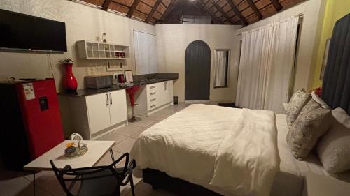 a bedroom with a bed and a table and a kitchen at Aneiwa airport lodge in Kempton Park