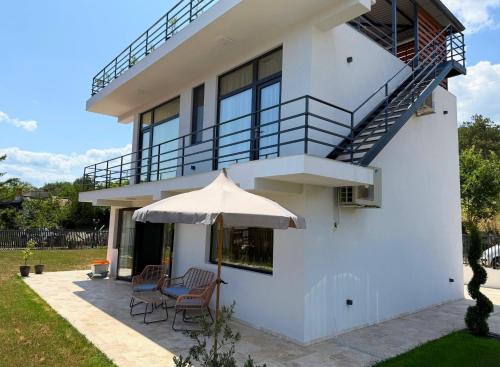 a white house with a patio and an umbrella at Villa Dilana in Balchik