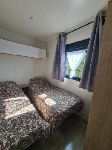 a bedroom with two beds and a window at Mobil-home Vue mer Piscine - Camping La Falaise Equihen-Plage - La Coquille d'Opale in Équihen-Plage