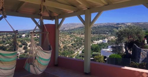 a porch with hammocks and a view of a valley at Villa Sunset with stunning sea view, kids area and hammocks on roof terrace in Agia Triada