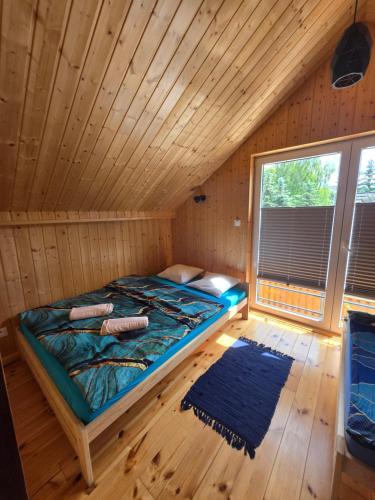 a bedroom with a bed in a wooden room at Nowy domek drewniany Tu Mi Dobrze w Lubkowie z plażą in Lubkowo