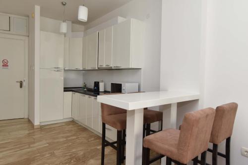 a kitchen with a white counter and two chairs at Apartments Menuet in Budva