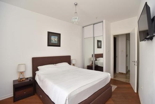 a bedroom with a large white bed and a television at Apartments Menuet in Budva