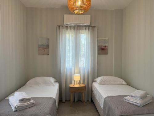 two twin beds in a room with a window at Villa Eleni Aegina in Egina