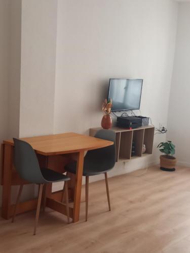une table en bois avec deux chaises et un bureau avec une télévision dans l'établissement Charmant T2 centre historique, à Perpignan