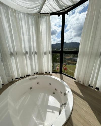 a white bath tub in front of a large window at Hotel Fazenda RosaBlue in Presidente Getúlio