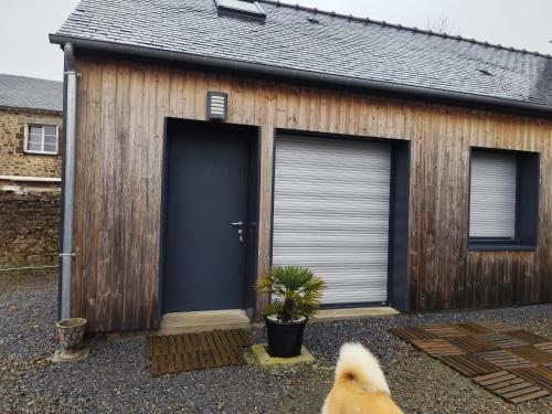 un chien est assis devant un garage dans l'établissement Les petits gites Ernée, à Ernée