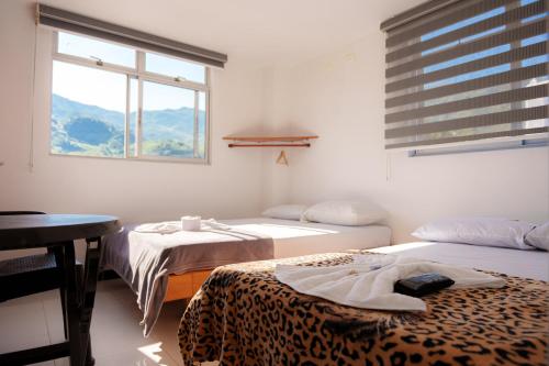 a room with two beds and a table and a window at Hotel Plaza Centro Cocorná in Cocorná
