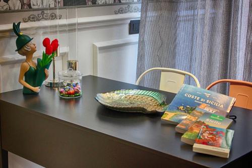 a table with a doll and a book and flowers at Roby's Boutique Rooms - Luxury B&B in Catania