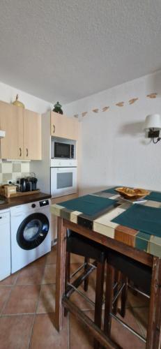 une cuisine avec une table et une cuisinière dans l'établissement Petit appartement aux Stes Maries de la Mer, à Saintes-Maries-de-la-Mer