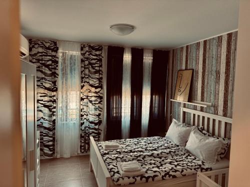 a bedroom with a bed and a wall with curtains at Apartment Beach Kavatsi in Sozopol