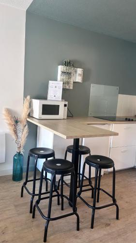 une cuisine avec une table avec quatre tabourets et un micro-ondes dans l'établissement La Venise du Languedoc Sète,Terrasse,mer,cosy, à Sète