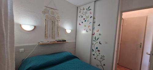 une chambre avec un lit avec des draps bleus et des papillons sur le mur dans l'établissement Petit appartement aux Stes Maries de la Mer, à Saintes-Maries-de-la-Mer