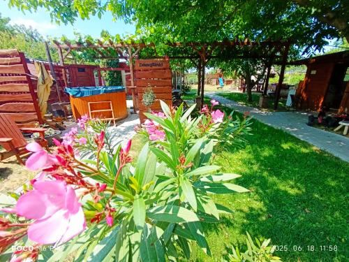a garden with pink flowers and a wooden bench at Robitel Wellness Vendégház Veszprém-Gyulafirátót in Veszprém
