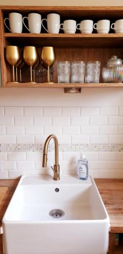 un comptoir de cuisine avec un évier blanc et une étagère avec de la vaisselle dans l'établissement Les Darons du Mont-Saint-Michel 14 people, à Pontorson