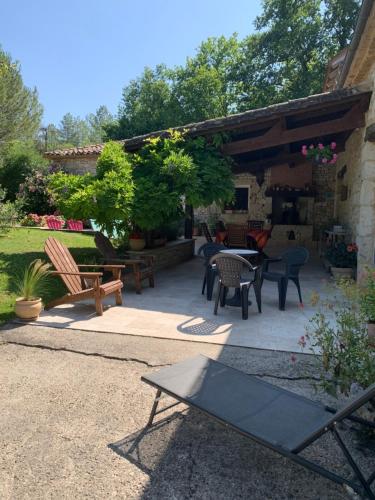 un patio avec des chaises et des tables dans un jardin dans l'établissement Au Bonheur des Oiseaux, à Larocal