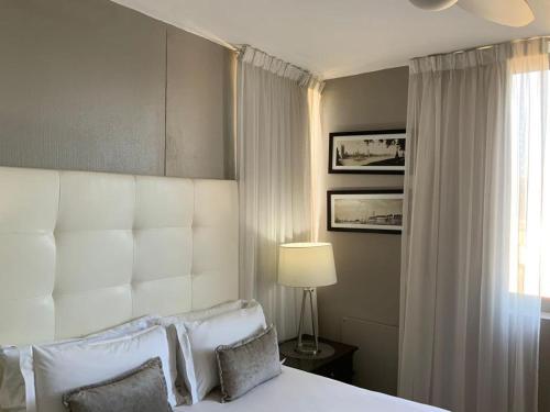 a bedroom with a bed with a white headboard and a window at Infinity Beach view in Cape Town
