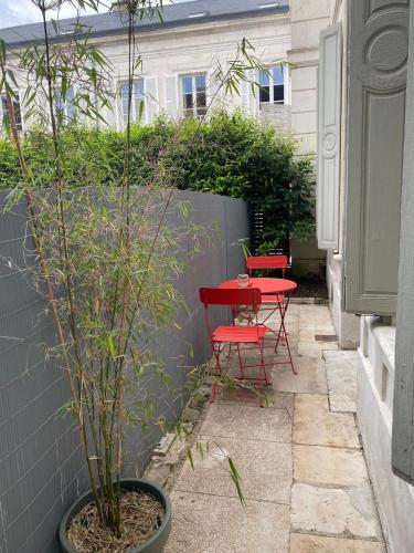 un patio avec une table rouge et deux chaises rouges dans l'établissement Le Philibert Roux, à Auxerre